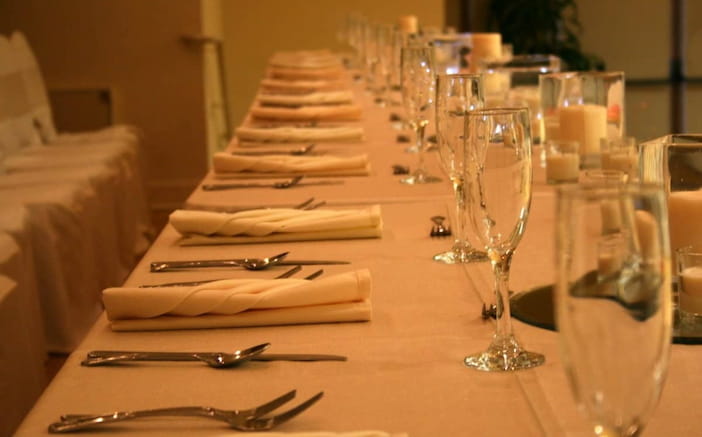 a table with white cover and red roses in the center.