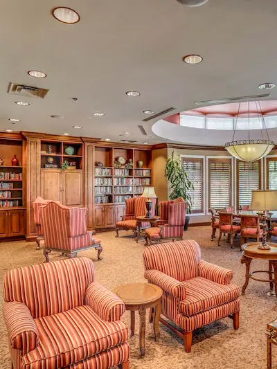 A library in the back with three large chairs in the foreground