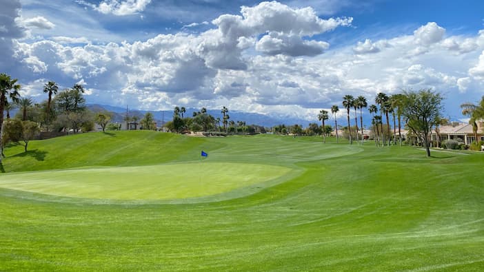 aerial view of a golf course with mountains in the background.